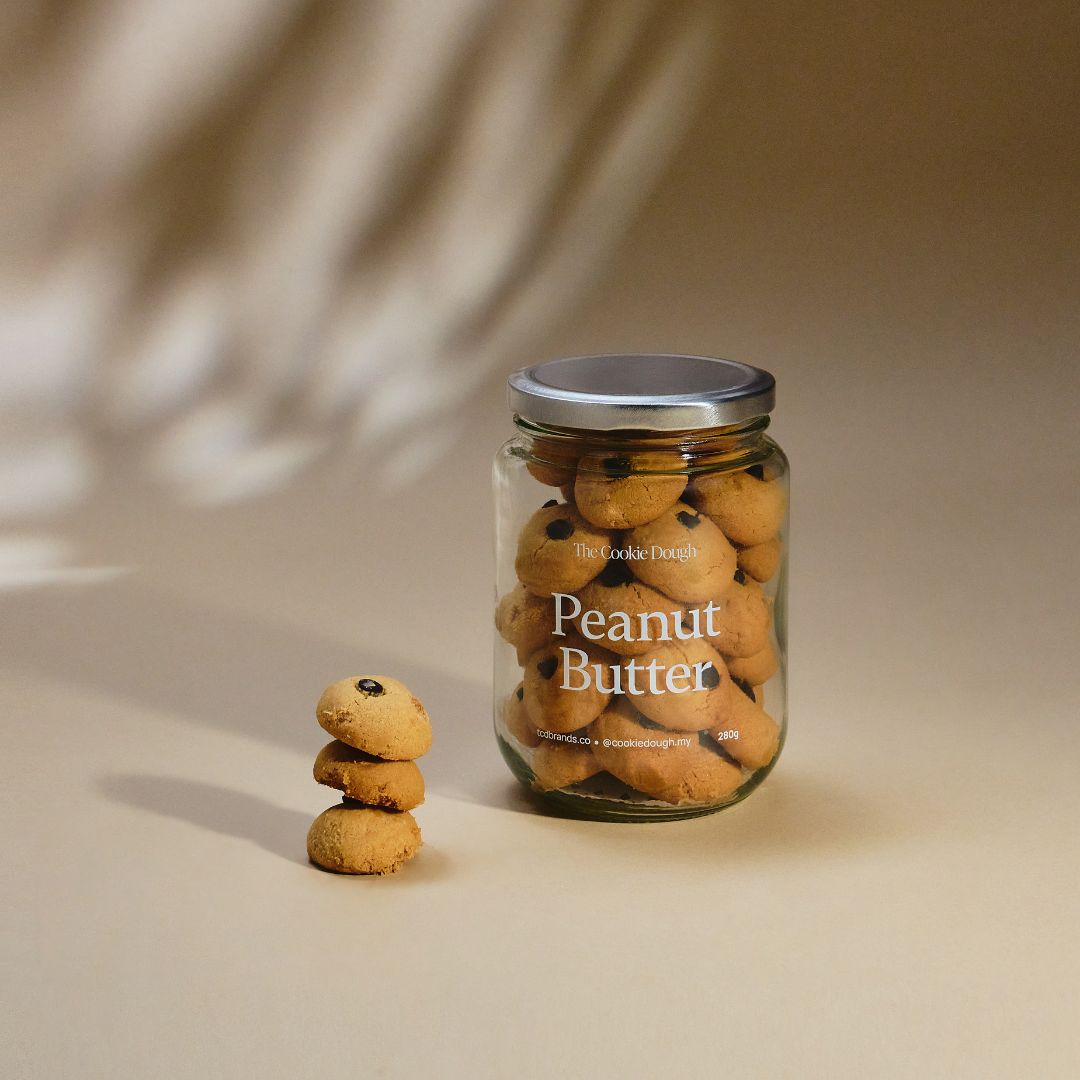 Jar of peanut butter cookies with a stack of cookies on a beige background